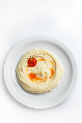 mashed potatoes with tomato on a white plate on a white background