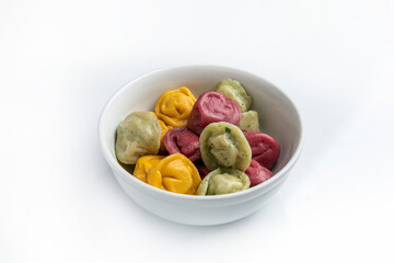 Multicolored dumplings in a bowl with sour cream.