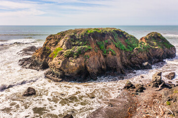 Stunning coastal landscape along California's Highway 1, featuring rugged rocky formations, and the vast blue ocean. A breathtaking natural scene showcasing the raw beauty of the Pacific coastline