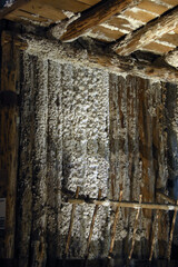Old wooden structure covered with crystalline salt deposits inside a historic salt mine. Atmospheric lighting highlights the texture and mineral buildup, showcasing the unique underground environment.