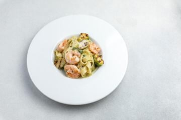 Tagliatelle pasta with shrimp and zucchini on white plate