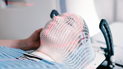A young woman wearing an immobilization mask undergoes computed tomography before radiation...
