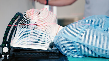 A young woman wearing an immobilization mask for radiotherapy lies in a CT capsule for precise...
