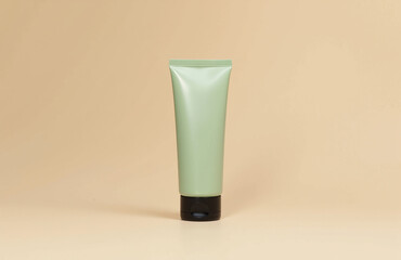 Minimalist green cosmetic tube on beige background with shadows.