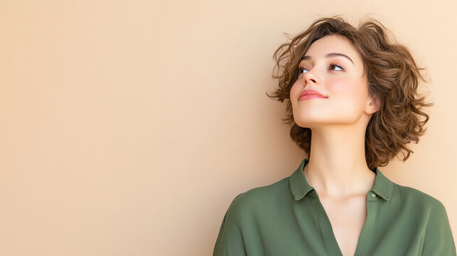 A young woman with curly hair smiles and looks thoughtfully upwards against a soft beige background, conveying a sense of serenity.
