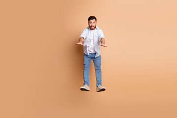 Trendy young man enthusiastically posing on a beige background displaying vibrant energy and casual...
