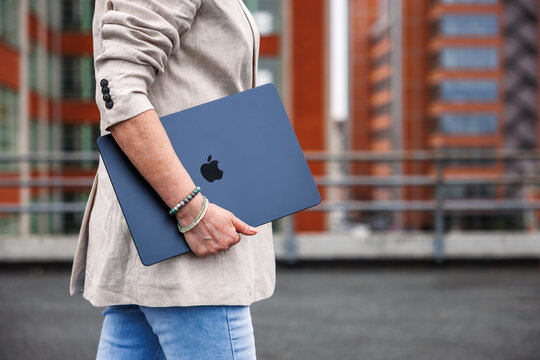 Businesswoman with Apple laptop MacBook Air walking outside of office building