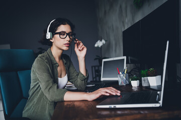 Young businesswoman wearing headphones and working on a laptop in a stylish indoor workspace
