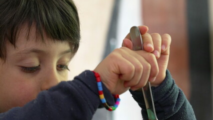 Young child fully engaged in twirling spaghetti with a fork, with a determined expression,...