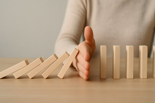 Hand Stopping Dominoes: A hand reaches out, palm facing the viewer, to stop a cascading row of dominoes, symbolizing a moment of intervention, resilience, and the ability to prevent a chain reaction.
