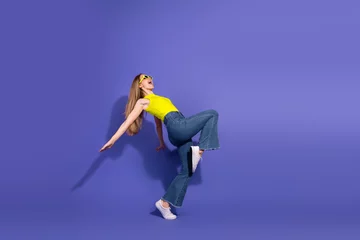 Fotobehang Youthful woman in casual fashion dancing energetically against a vibrant modern violet backdrop highlighting a stylish lifestyle © deagreez