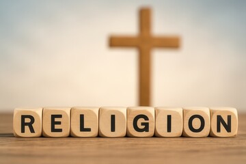 Wooden cubes composing the word religion with blurred cross in background