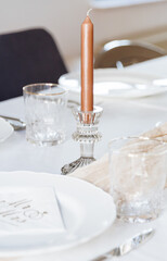 A candle in a crystal candlestick on a festive table.