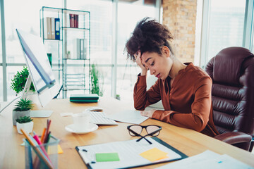 Stressed young businesswoman working overtime in a modern office with natural daylight, showcasing...