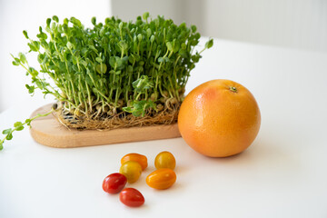 Bright culinary ingredients, vegetables and microgreens are laid out on the table near the wooden...