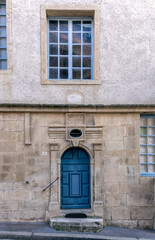 Old building facade featuring wooden door, iron balcony, and geometric stone wall pattern.For the background of your photos and collages.