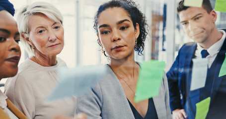 Obraz premium Planning, glass wall and writing with business people in office for diversity or strategy. Brainstorming, collaboration and sticky notes with employee team in workplace for discussion or management