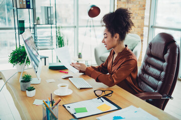 Young professional businesswoman working in a modern office workspace with daylight and...