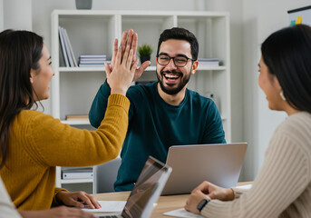 Enthusiastic workplace colleagues high-fiving each other in a business office setting