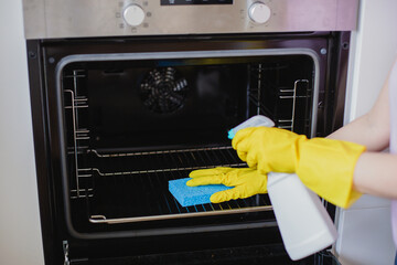 Cropped hands of woman cleaning oven at home
