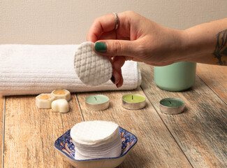 una mano de mujer con las uñas pintadas tomando un pétalo desmaquillante