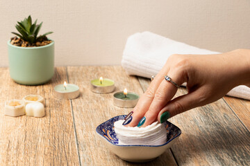 una mano de mujer con las uñas pintadas tomando un pétalo desmaquillante