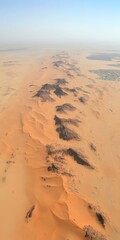 Aerial View of Desert Landscape with Sand Dunes and Dark Rock Formations