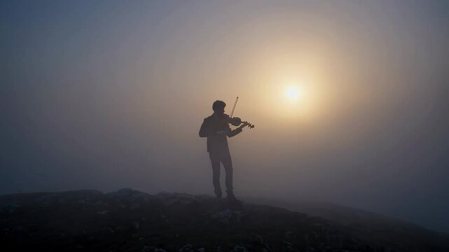 Silhouette of violinist in misty sunrise on mountain top capturing tranquil harmony