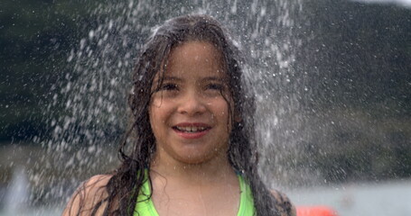 Fototapeta premium Girl smiling under a shower of water in slow-motion at 800 fps, enjoying the outdoors, background softly blurred, water droplets visible
