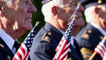 Senior military veterans wearing uniforms, standing solemnly while holding small american flags during national remembrance ceremony, honoring military service and sacrifice - Powered by Adobe