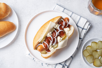 Pickled cucumbers fresh onion frankfurter sausage hot dog sandwich on a white background
