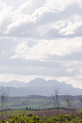 Scenic view of rolling green fields and distant mountains under a cloudy sky. A tranquil rural landscape showcasing natural beauty and peaceful countryside atmosphere.