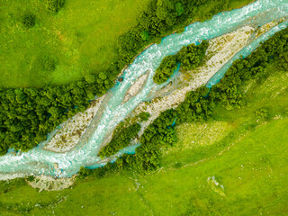 Mountain river with green trees and fresh green grass. Aerial top down view.