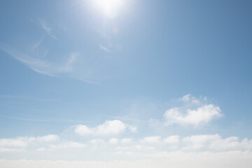 Blue sky with white clouds and sun with sunbeams at sunny day. Abstract nature background.