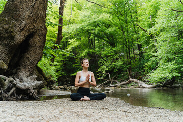 Young woman meditating and practicing yoga on nature. Holistic Health and Mental Well-Being.