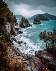 Dramatic Coastal Scene of Montenegro featuring Rocky Cliffs Turquoise Water and Distant Mountains under a Cloudy Sky showcasing the rugged beauty of the Adriatic Coast