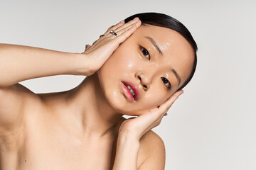 Radiant young asian woman showcasing natural beauty in a minimalist studio setting