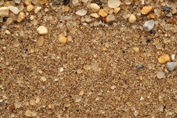Close-up view of beach sand mixed with small stones and pebbles.