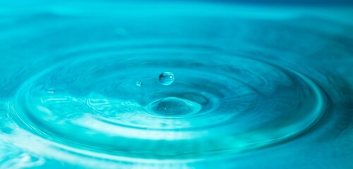 Water droplets fall down closely into the blue water, making it the perfect center in nature