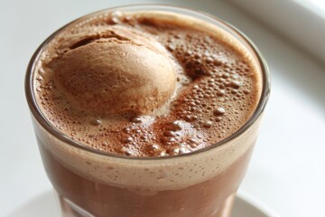 Delicious hot chocolate with melting ice cream in a clear glass on a white table top close up capturing the creamy texture and inviting warmth for a cozy indulgence