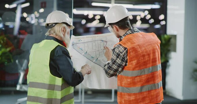 Construction workers diligently analyzing detailed blueprint plans for effective building execution