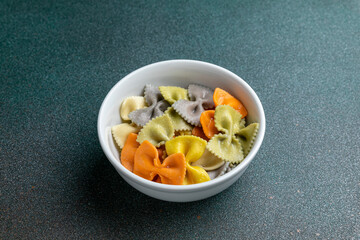 colorful farfalle pasta in a bowl on white marble background
