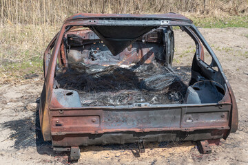 Burnt and rusty charred car close-up. Damaged automobile in consequence of accident and disaster....