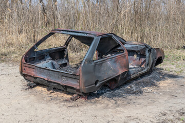 Burnt and rusty charred car close-up. Damaged automobile in consequence of accident and disaster....