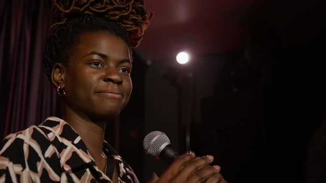 Close-up shot of female African American stand-up artist interacting with audience dueing her performance on stage