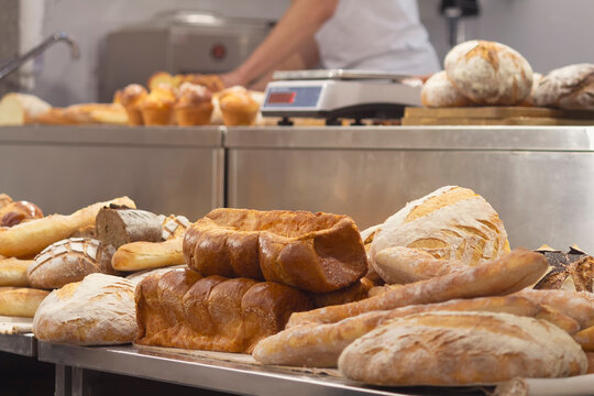 Fresh delicious bread on the counter in a bakery and a baker in the background - Powered by Adobe