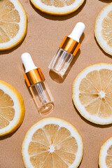 Two transparent serum dropper bottles with golden caps placed on textured beige background, surrounded by fresh lemon slices. Clean, elegant skincare flat lay for beauty and citrus-themed ads