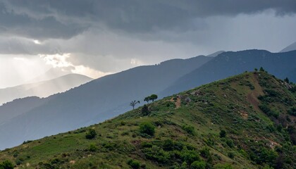 Rain falling over a mountain ridge under thick storm clouds as sunlight breaks through in the distance