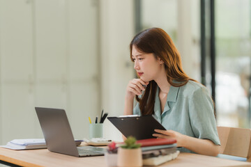 Obraz premium Focused Asian Woman Working at Desk