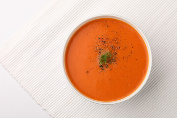 Tomato Soup garnished with pepper powder and mint leaf, served in ceramic bowl